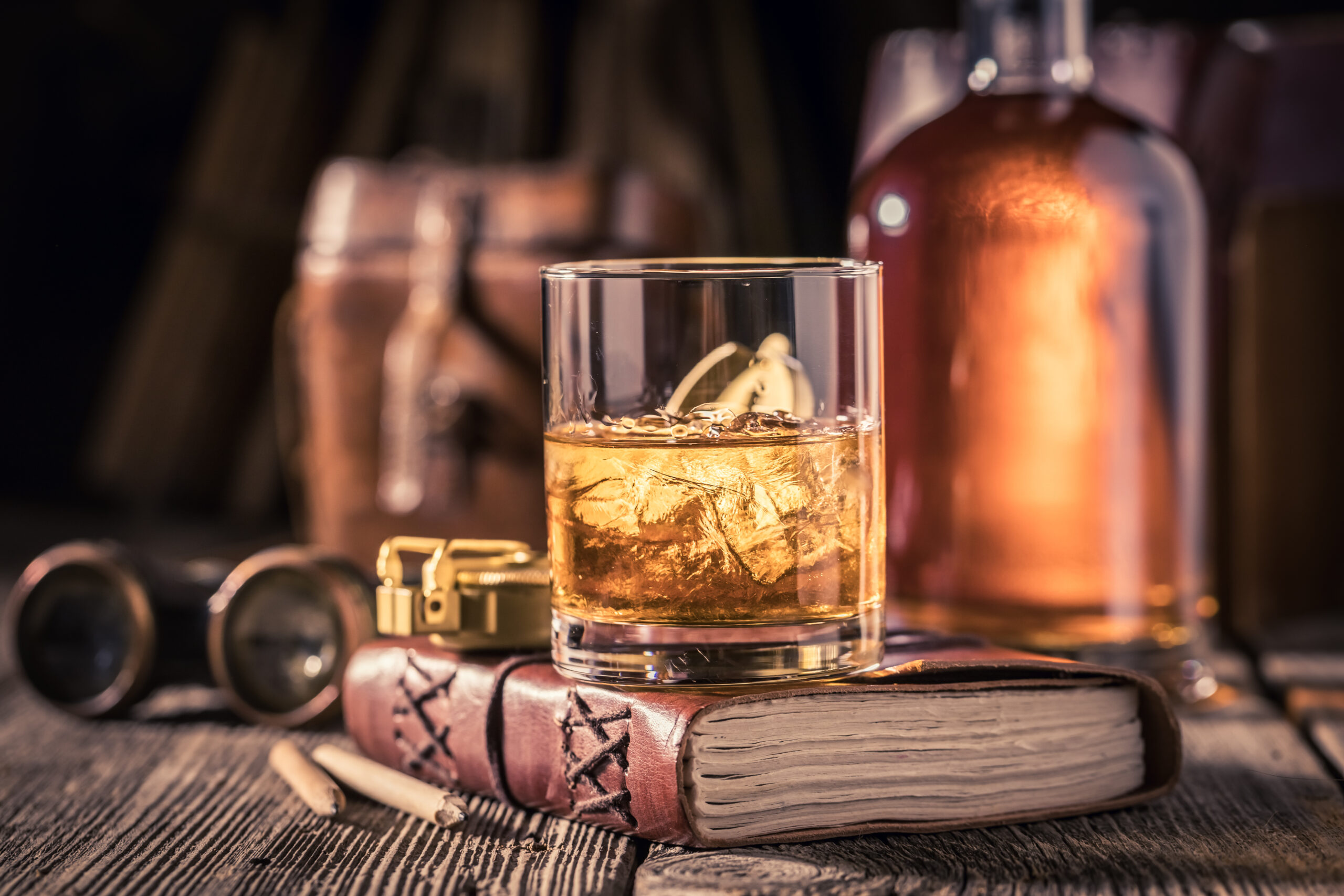 ein gefülltes Glas Whisky auf einem Buch stehend, mystische Stimmung
